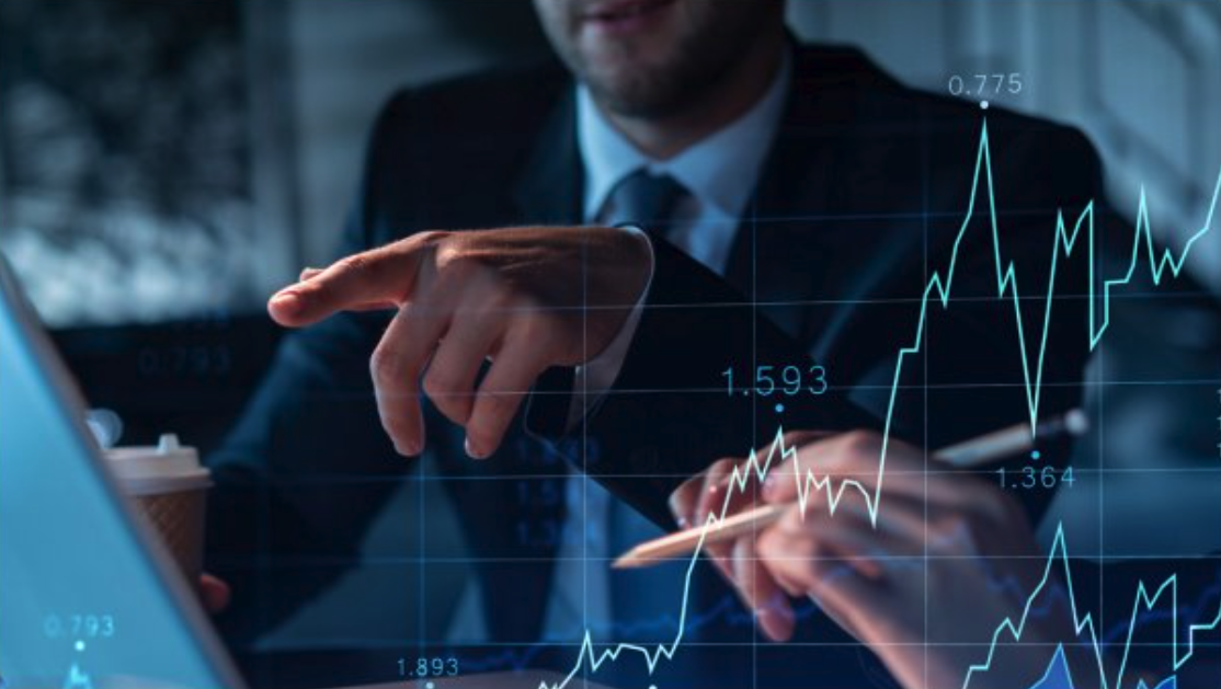 Dos personas con vestimenta profesional revisan gráficos financieros superpuestos en la pantalla de un portátil